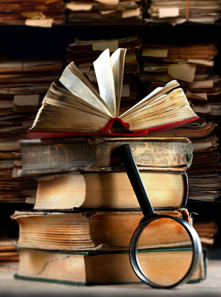 A stack of books with a magnifying glass